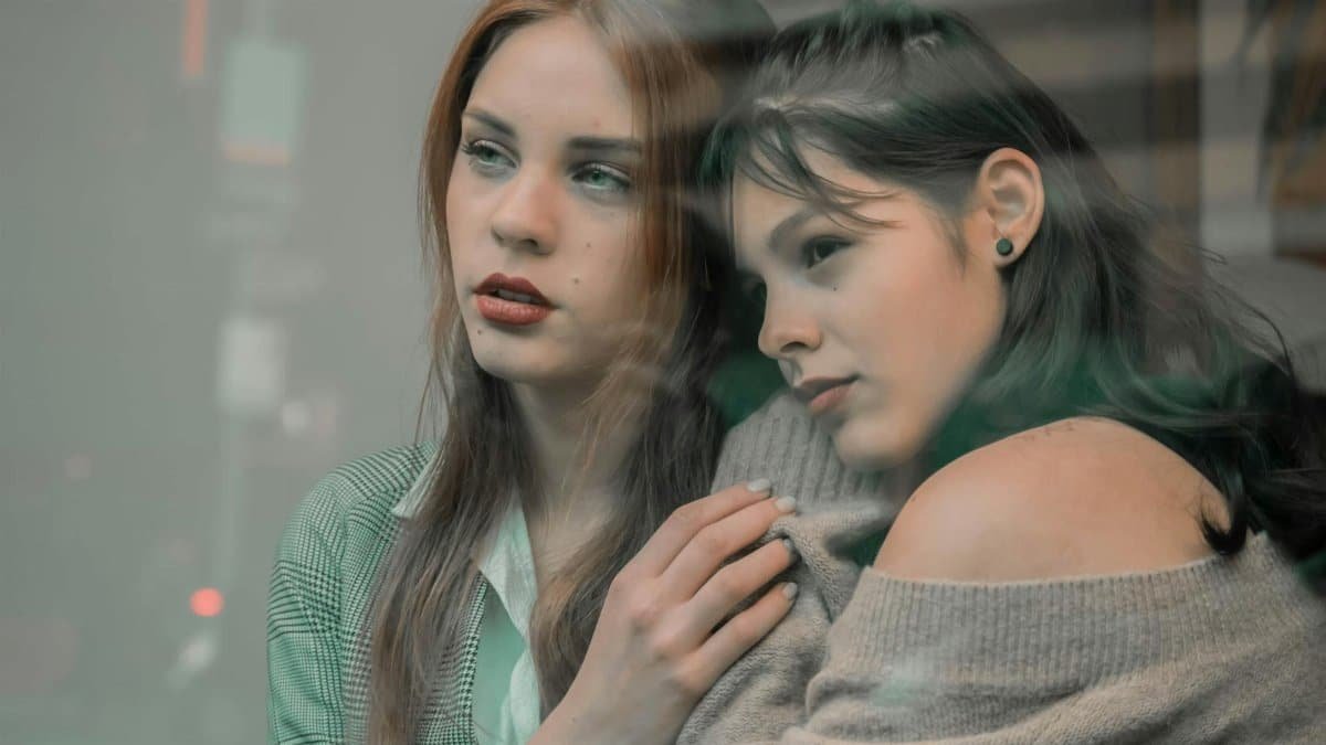 Two women sharing an emotional moment through a glass window, indoors.