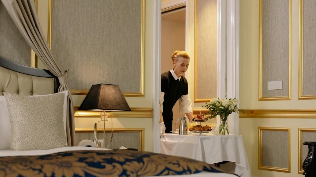 A hotel employee delivers elegant room service with a tray of breakfast in a luxurious hotel setting.