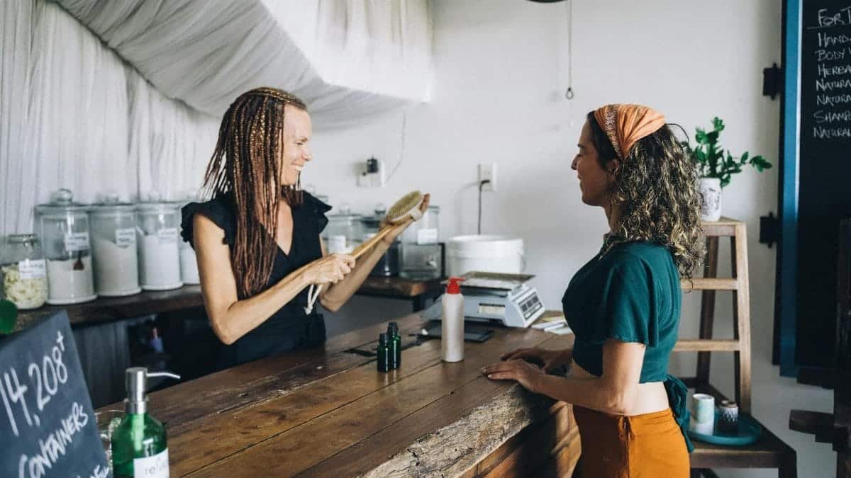 Two women in an eco-friendly store with refillable containers and glass jars.