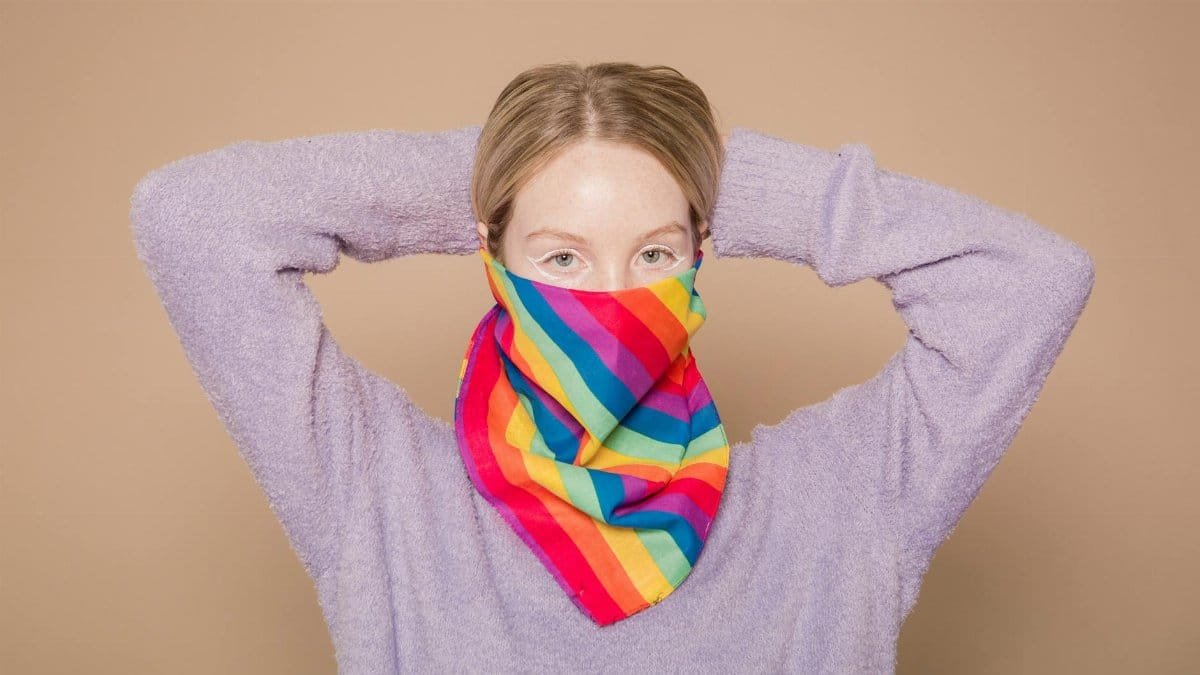 Young woman wearing colorful scarf posing calmly in studio with hands behind head.