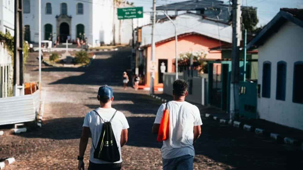 Two men walk on a sunny day in a charming town street with colorful houses.
