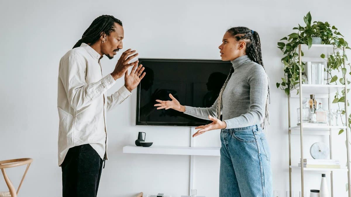 A young couple engaged in a tense argument in their modern living room setting.