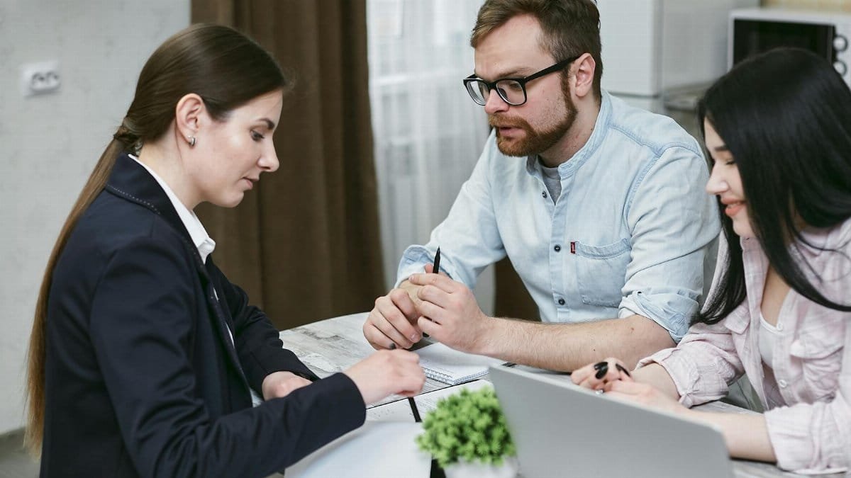 A couple discusses financial documents with their advisor, highlighting investment strategies.