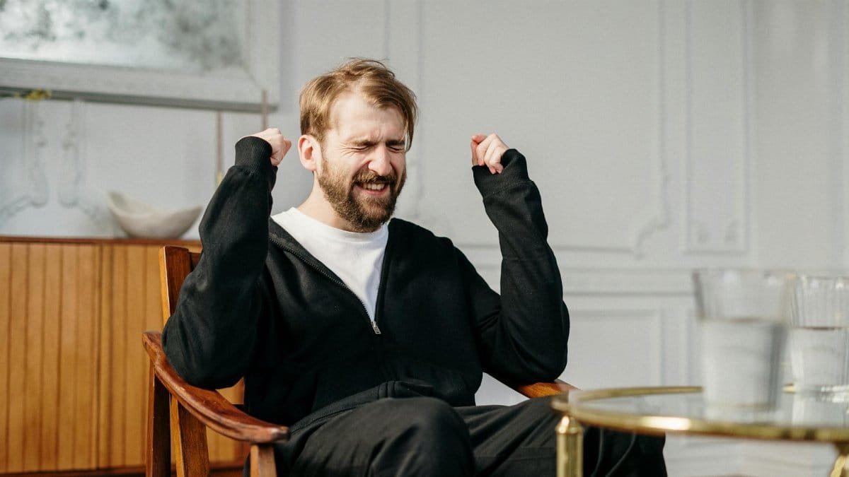 A bearded man expressing emotional distress in a modern interior setting, seeking mental health support.