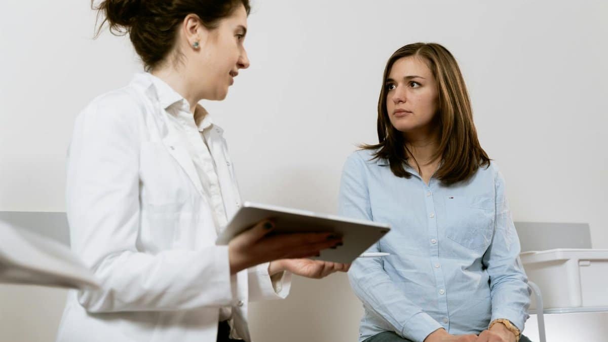A doctor consults with a pregnant patient discussing healthcare options in a medical facility.