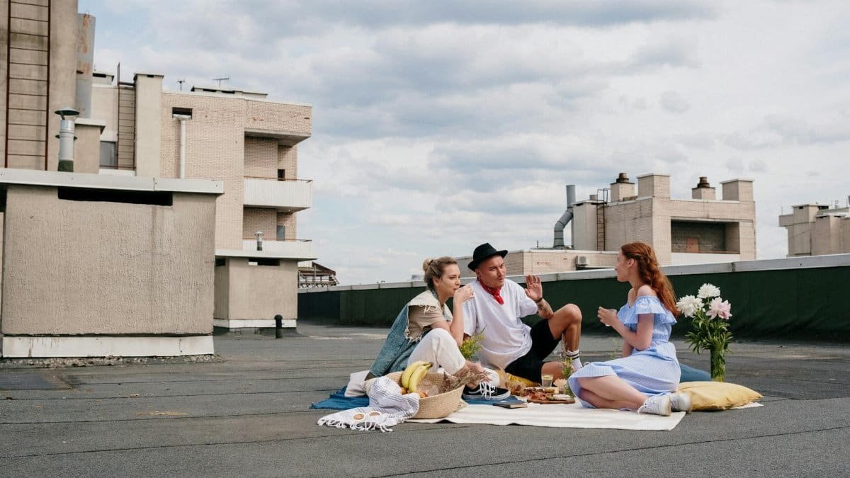 Group of friends enjoying a sunny rooftop picnic with food and laughter.