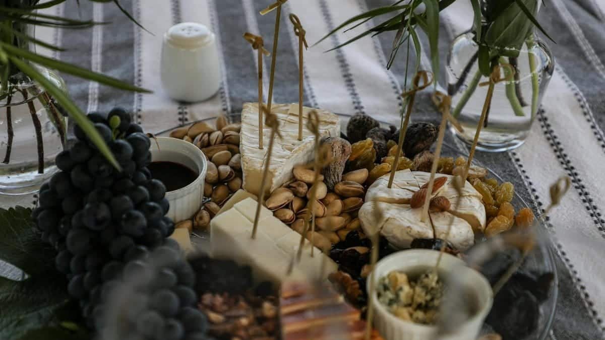 Delicious assortment of cheeses with grapes and nuts on a table setting.