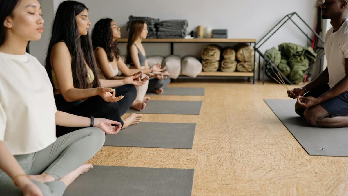 A multicultural yoga class practicing meditation and mindfulness indoors.
