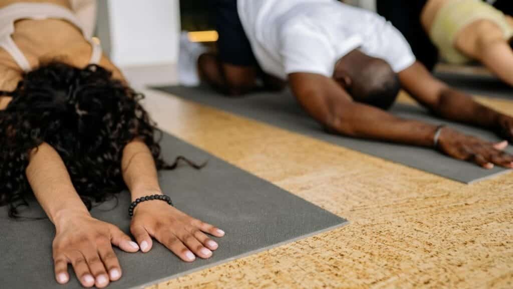 A diverse group of people stretching on yoga mats in a studio, focusing on fitness and relaxation.