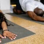 A diverse group of people stretching on yoga mats in a studio, focusing on fitness and relaxation.