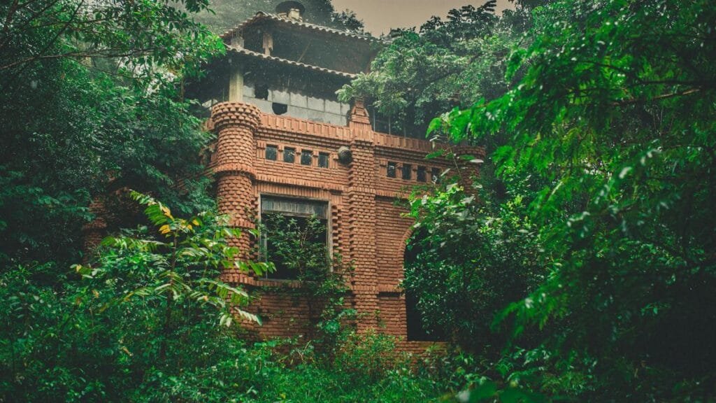 Ancient brick building enveloped by lush jungle greenery, exuding mystery and history.