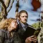 A couple standing in a cemetery, reading from the Bible, signifies faith and companionship.