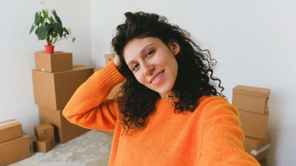 Cheerful woman moving into new apartment, surrounded by boxes.