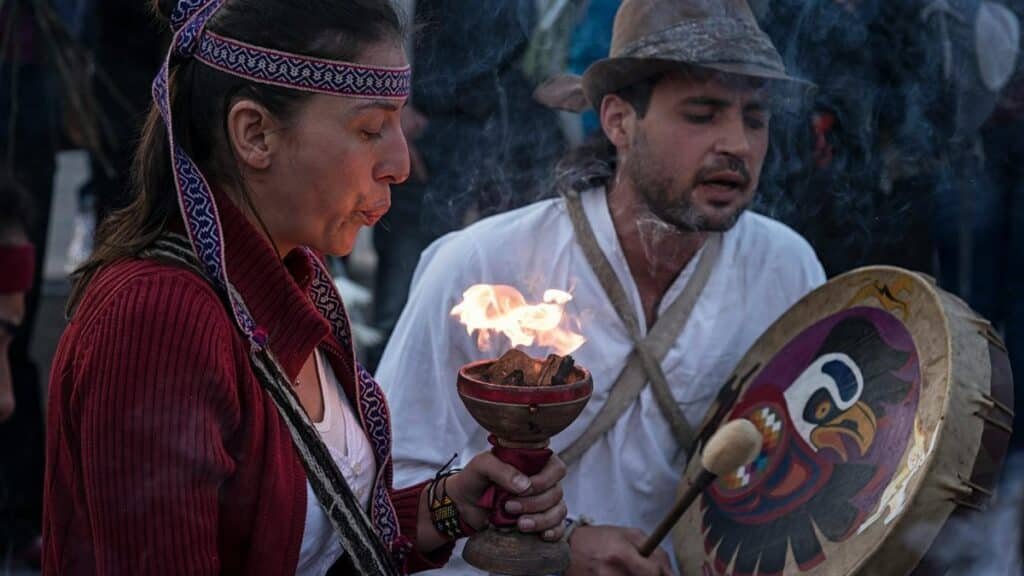 Cultural ritual with fire and music in Bogotá, Colombia, showcasing traditional attire and instruments.