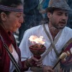 Cultural ritual with fire and music in Bogotá, Colombia, showcasing traditional attire and instruments.