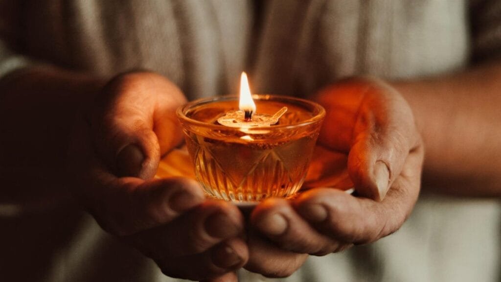 A warm, intimate close-up of hands holding a flickering candle flame, symbolizing hope.