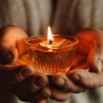 A warm, intimate close-up of hands holding a flickering candle flame, symbolizing hope.
