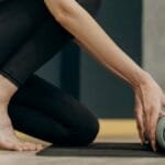 A woman rolling out a yoga mat for an indoor fitness routine, emphasizing calmness and focus.