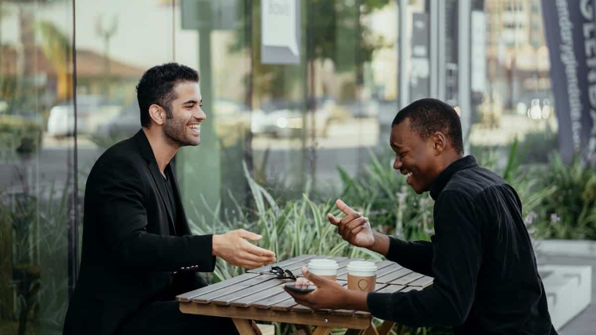 Two friends enjoy a lively conversation over coffee at an outdoor café.