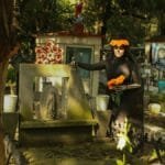 Woman dressed for Día de los Muertos in a cemetery, adorned with marigolds.