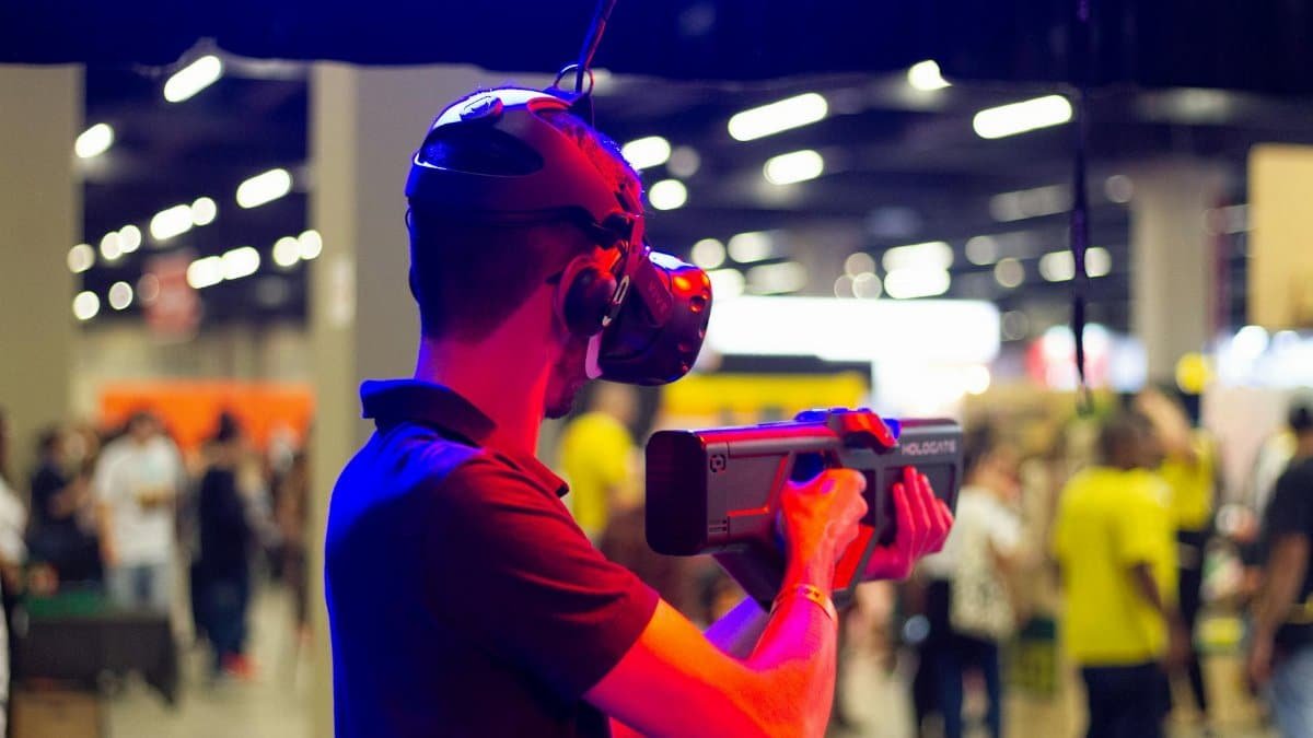 Back view of young male in casual clothes and VR headset standing in spacious hall while testing device operation