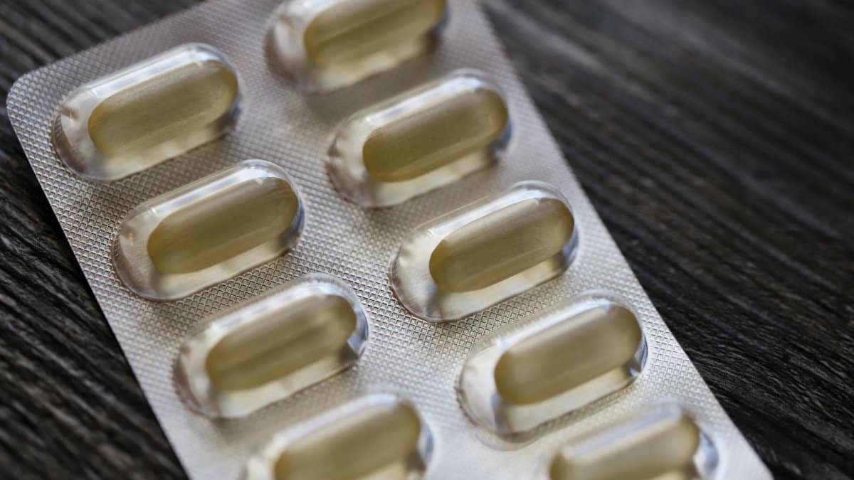 Detailed view of a blister pack with transparent capsules on a textured wooden background.