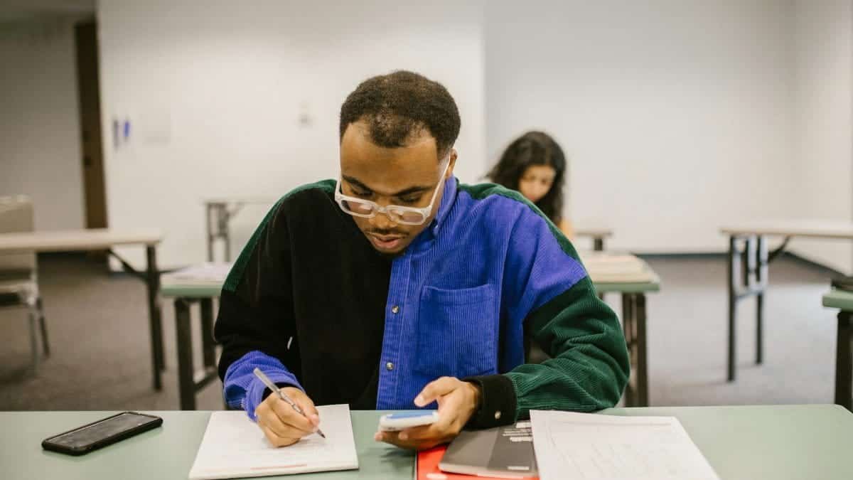 Focused college student with calculator and notes during classroom examination.