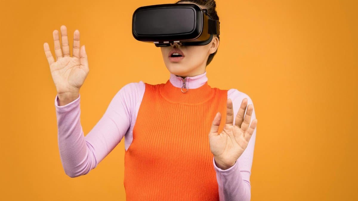 A woman wearing a VR headset immersed in a virtual reality experience against an orange background.