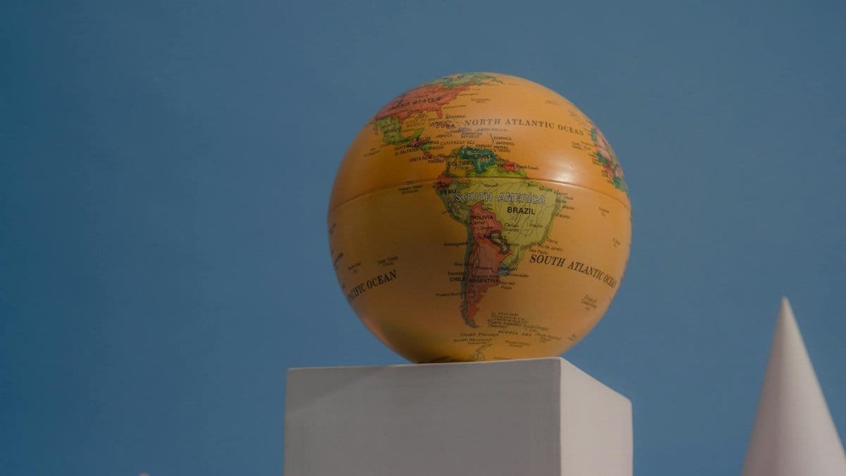 A vibrant globe on geometric shapes against a blue backdrop, showcasing continents and oceans.