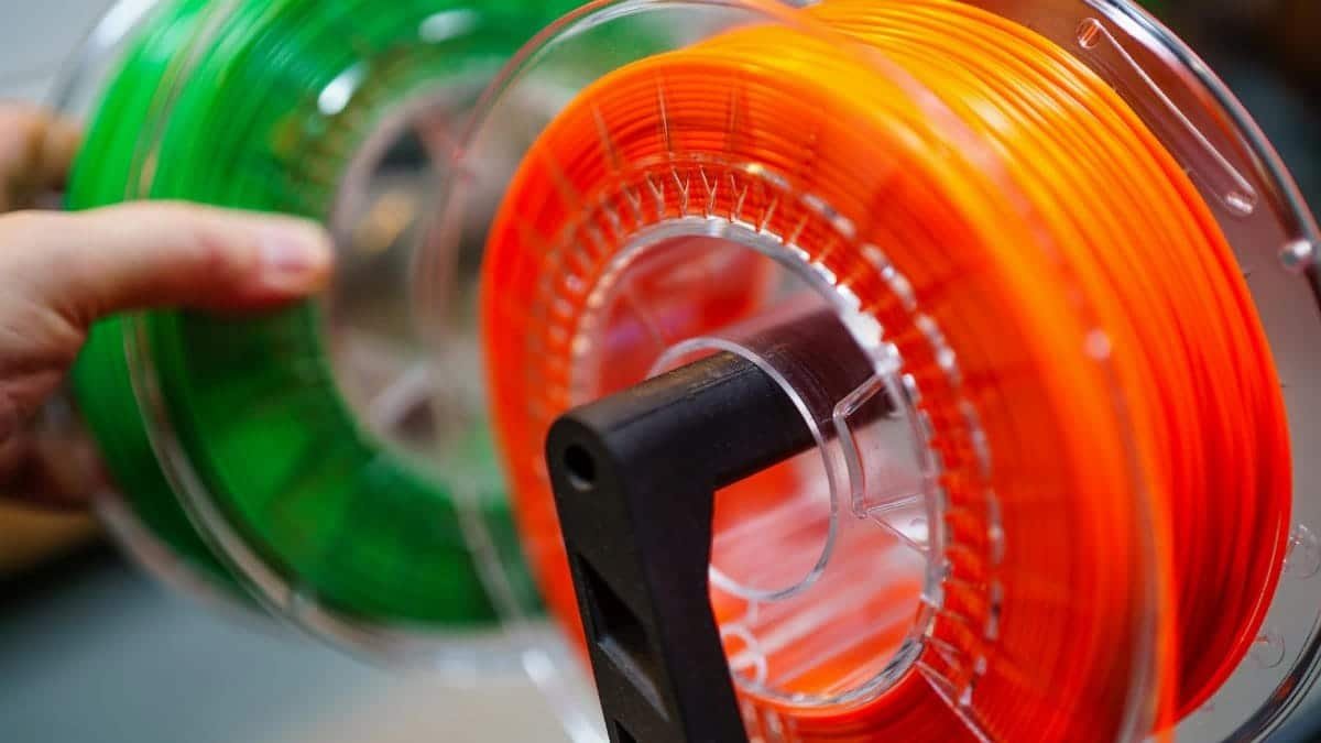 Vibrant orange and green 3D printer filament spools for innovative manufacturing uses.