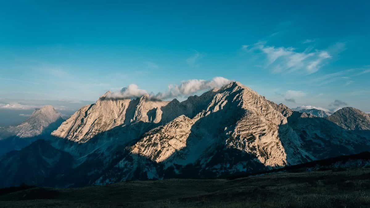 Beautiful mountain landscape with sunlight and clouds highlighting the peaks at sunrise.