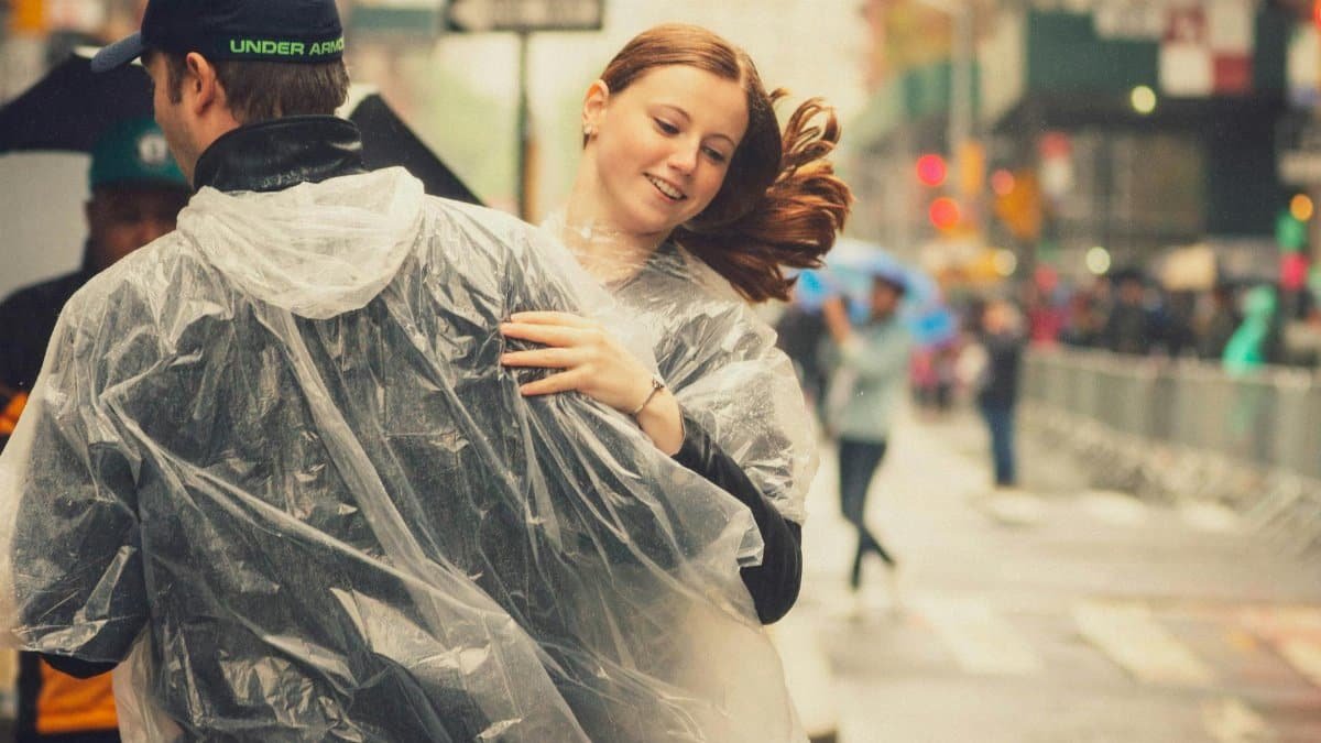 Couple dancing joyfully in the rainwear during a street festival in New York City.