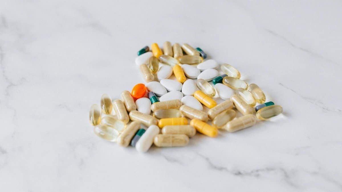 Close-up of various pills and supplements on a marble background, symbolizing health care and wellness.
