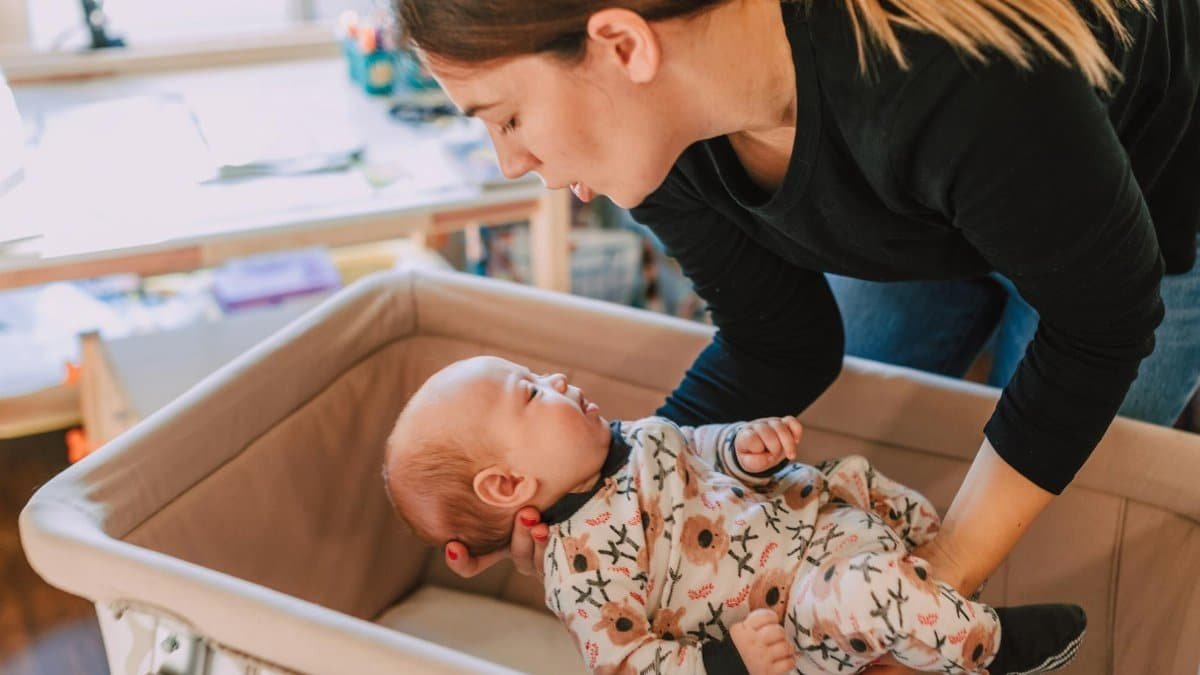 A mother lovingly interacts with her baby in a cozy nursery setting, emphasizing parental affection.