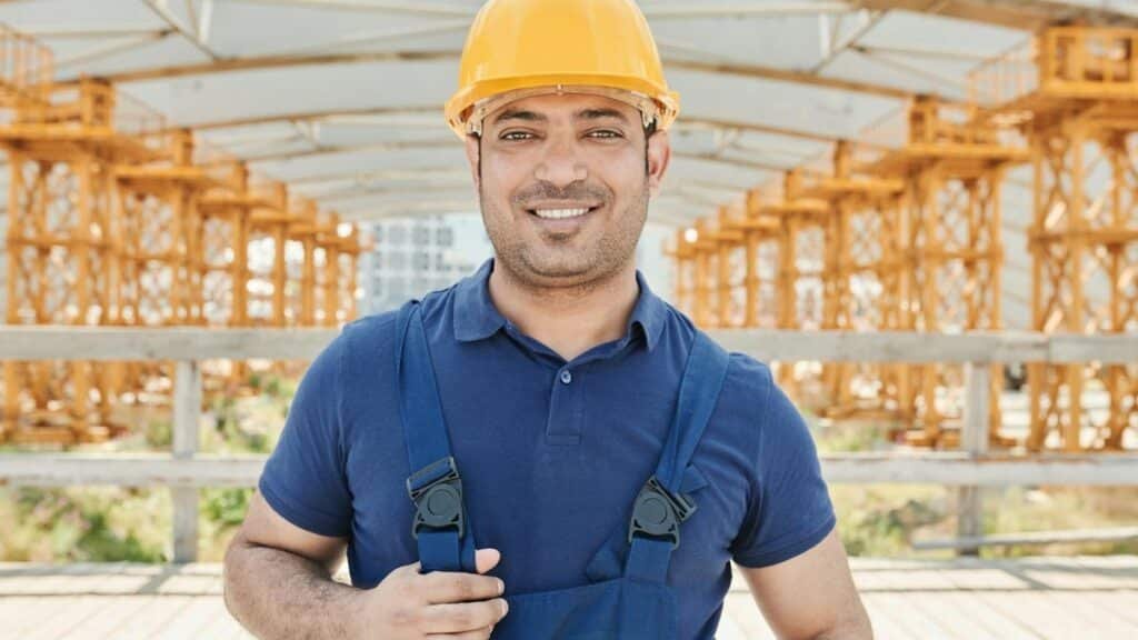 Confident construction worker wearing a hard hat and safety gear on-site.