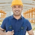 Confident construction worker wearing a hard hat and safety gear on-site.