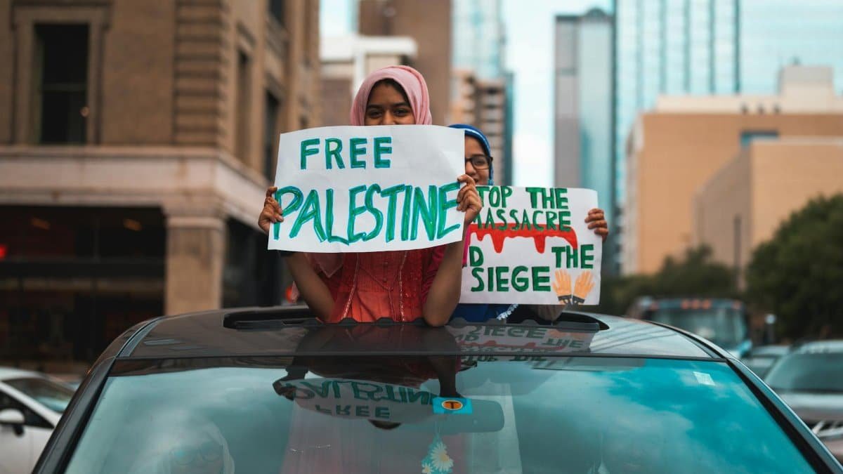 Two individuals holding 'Free Palestine' signs during a peaceful protest in a city center.