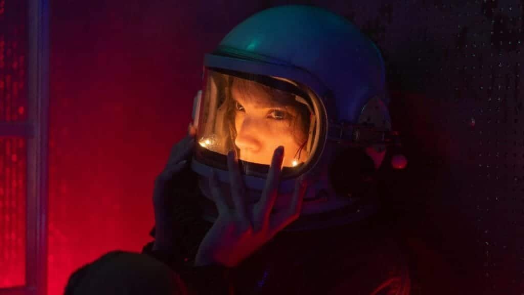 Dramatic close-up portrait of a woman in an astronaut helmet with vibrant lighting.