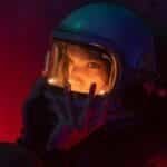 Dramatic close-up portrait of a woman in an astronaut helmet with vibrant lighting.