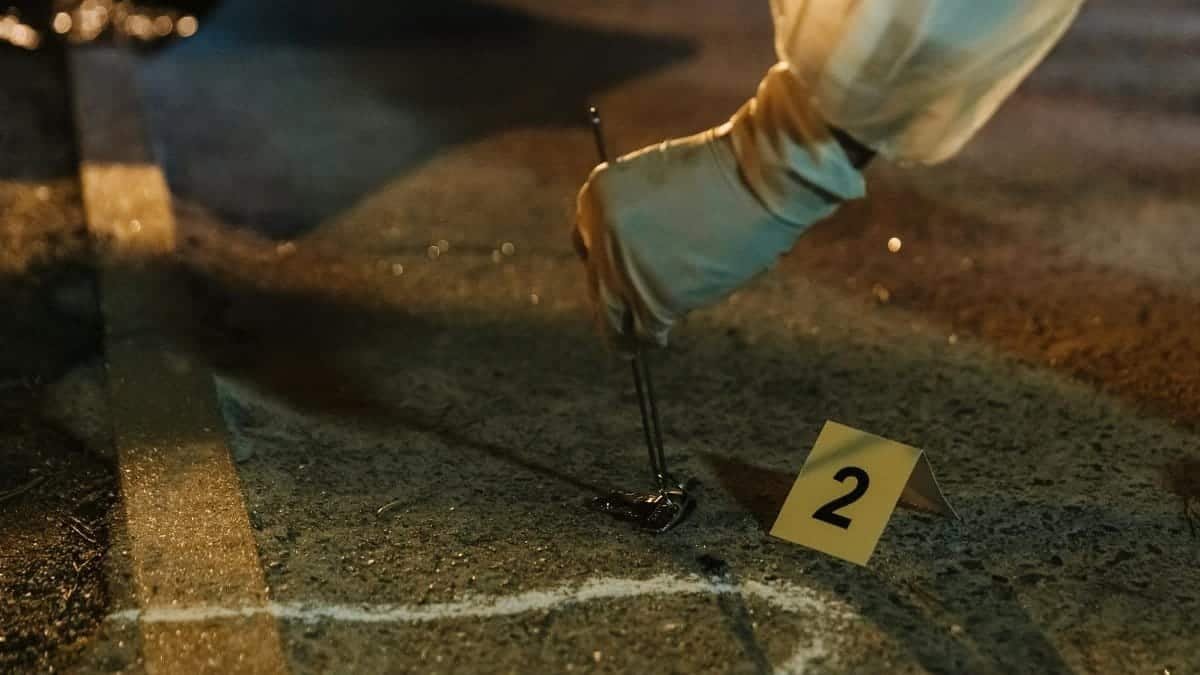 Close-up of a forensic investigator collecting evidence at a night crime scene with gloved hands.