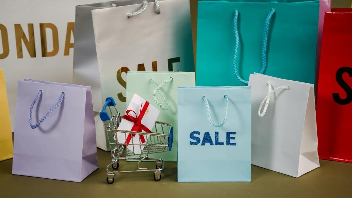 A mix of colorful shopping bags and a small cart displaying a discount gift.
