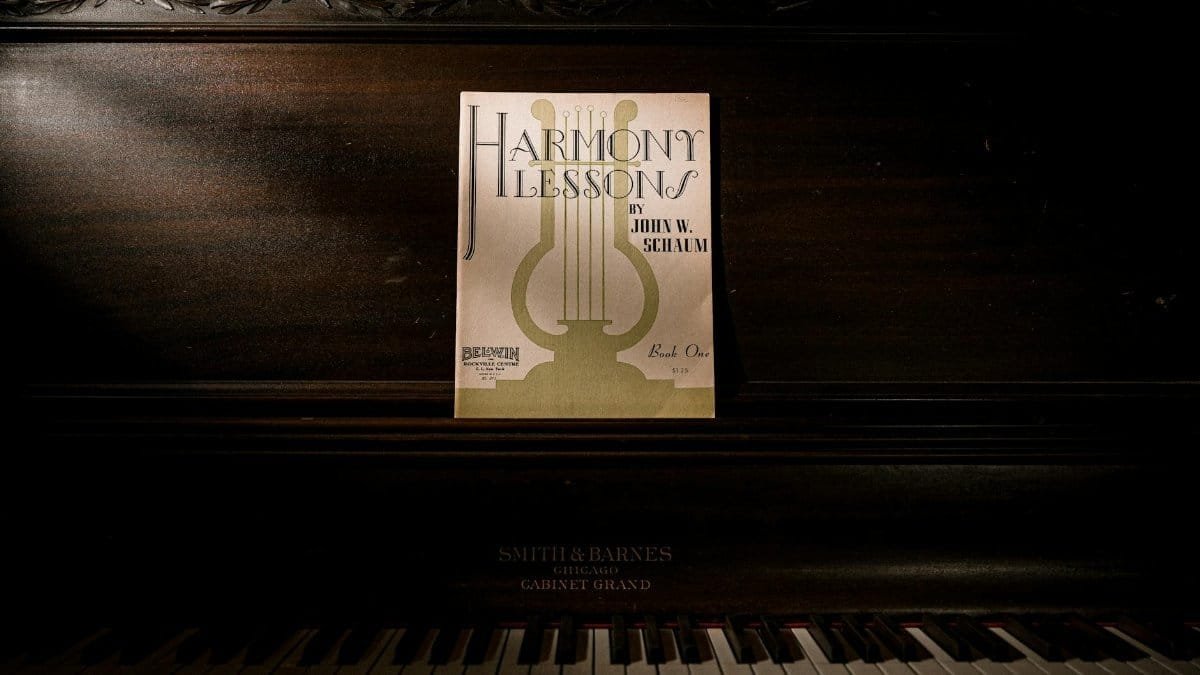 Dark, vintage piano with 'Harmony Lessons' sheet music, offering a classic and artistic ambiance.