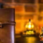 Leather journal with vintage key and potion bottles on rustic background.