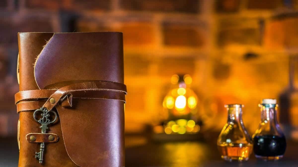 Leather journal with vintage key and potion bottles on rustic background.