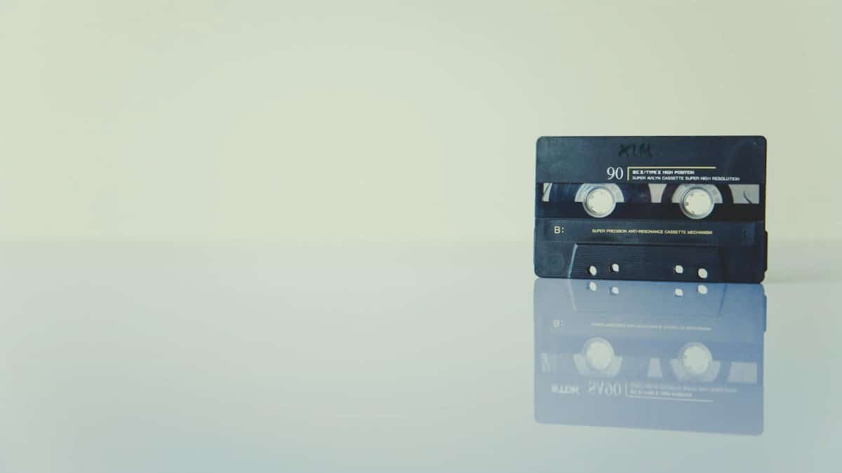 Retro cassette tape on a reflective surface, evoking nostalgia and vintage music vibes.