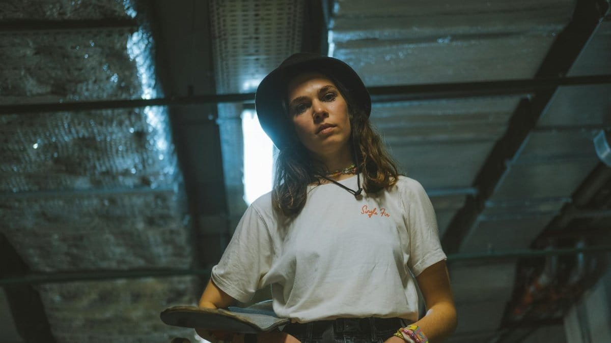 Portrait of a young woman holding a skateboard, exuding a cool and casual vibe.