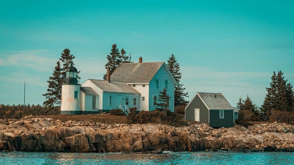 Scenic view of a coastal lighthouse and house on rocky shores in Maine, USA. Ideal for travel inspiration.