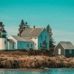 Scenic view of a coastal lighthouse and house on rocky shores in Maine, USA. Ideal for travel inspiration.