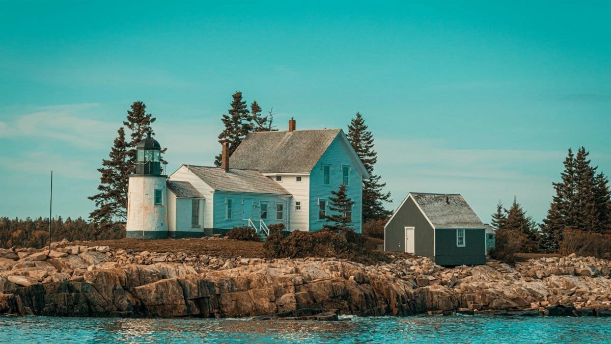 Scenic view of a coastal lighthouse and house on rocky shores in Maine, USA. Ideal for travel inspiration.