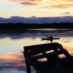 Serene lake view with silhouetted canoeist at sunset in Scarborough, Maine.
